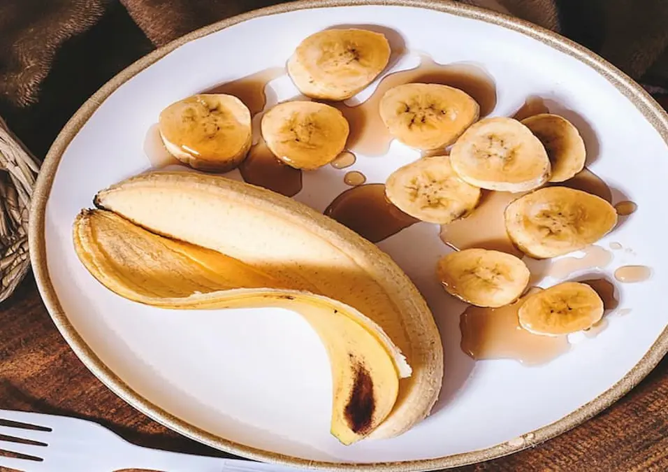 موز مقشر ومقطع على طبق، مع قليل من الشراب، يقدم دليلاً كاملاً للسعرات الحرارية في الموز حسب الحجم والوزن.