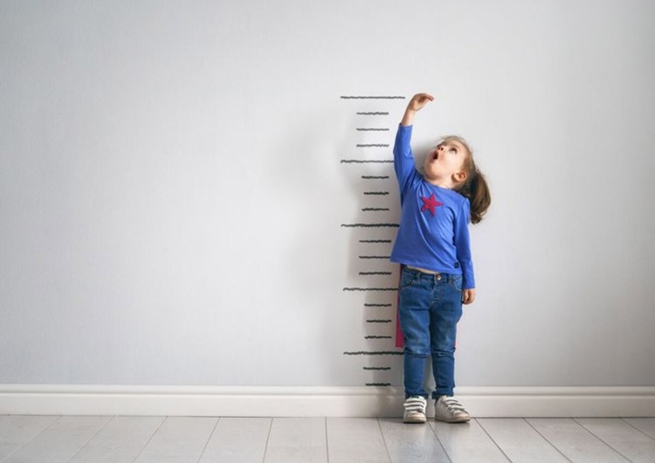 A little girl measures her height