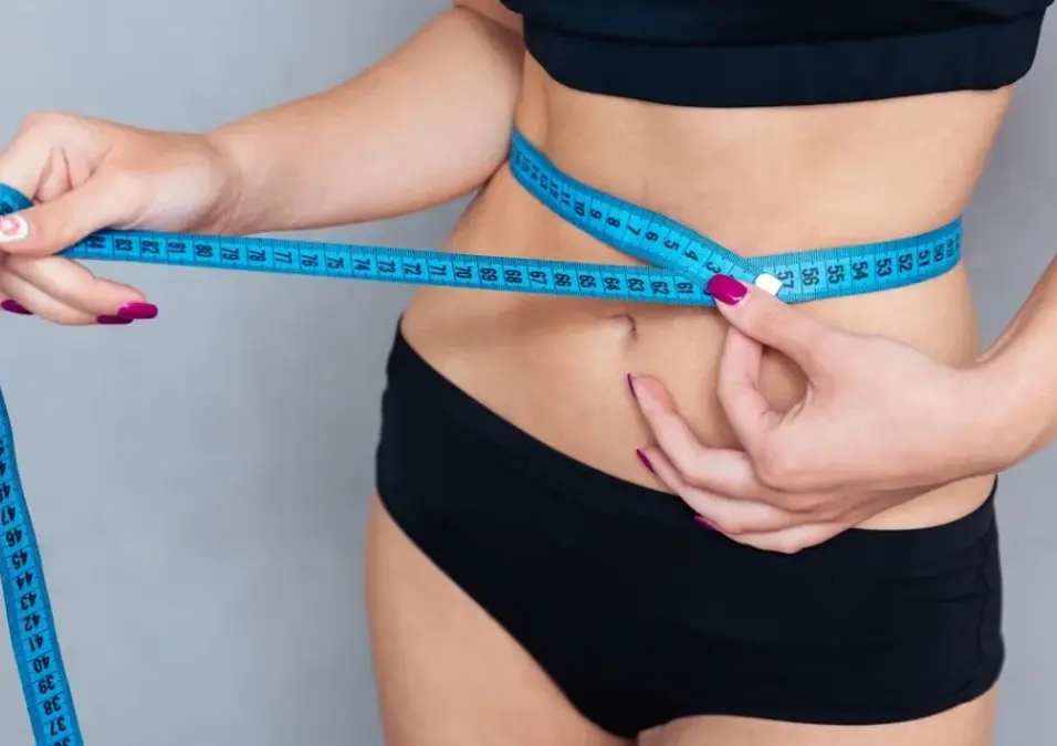 Woman measuring waist with blue tape measure