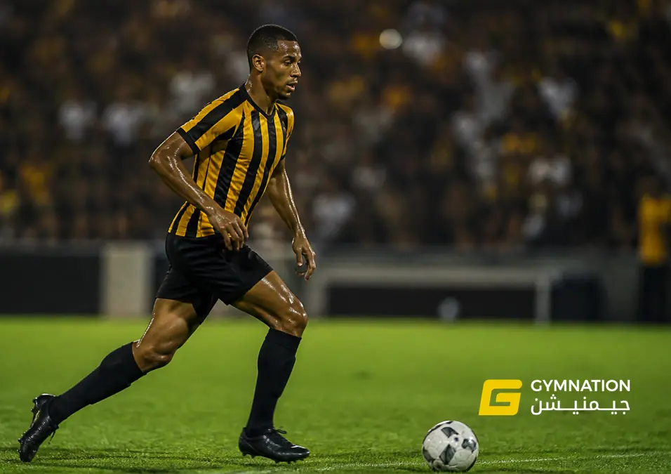 A player in a yellow and black striped jersey runs on a vibrant field, illuminated by stadium lights. The crowd is blurred in