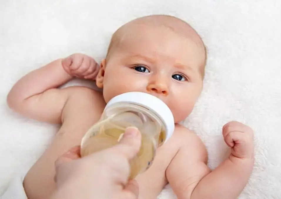 طفل يتم إرضاعه بعبوة تحتوي على سائل فاتح اللون، مما يوحي بفوائد الشمر للأطفال وهل يساعد فعلاً في تهدئة المغص.