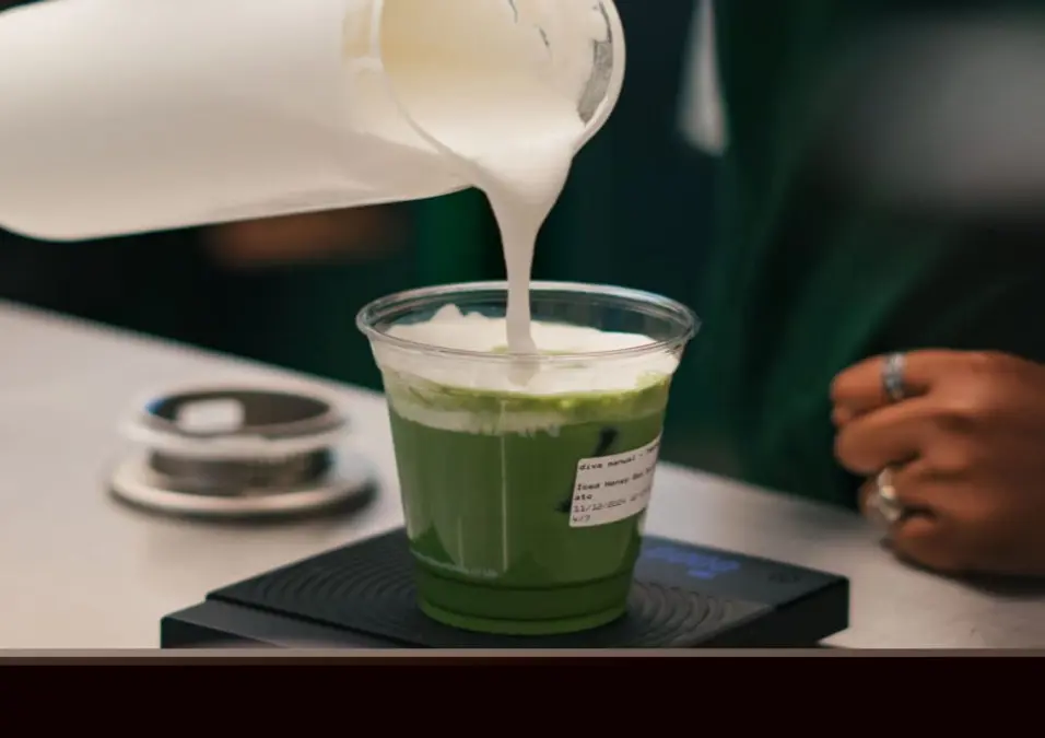 حليب يُسكب في مشروب ماتشا أخضر، يوحي بفوائد الماتشا مع الحليب كمشروب صحي بطعم مميز.