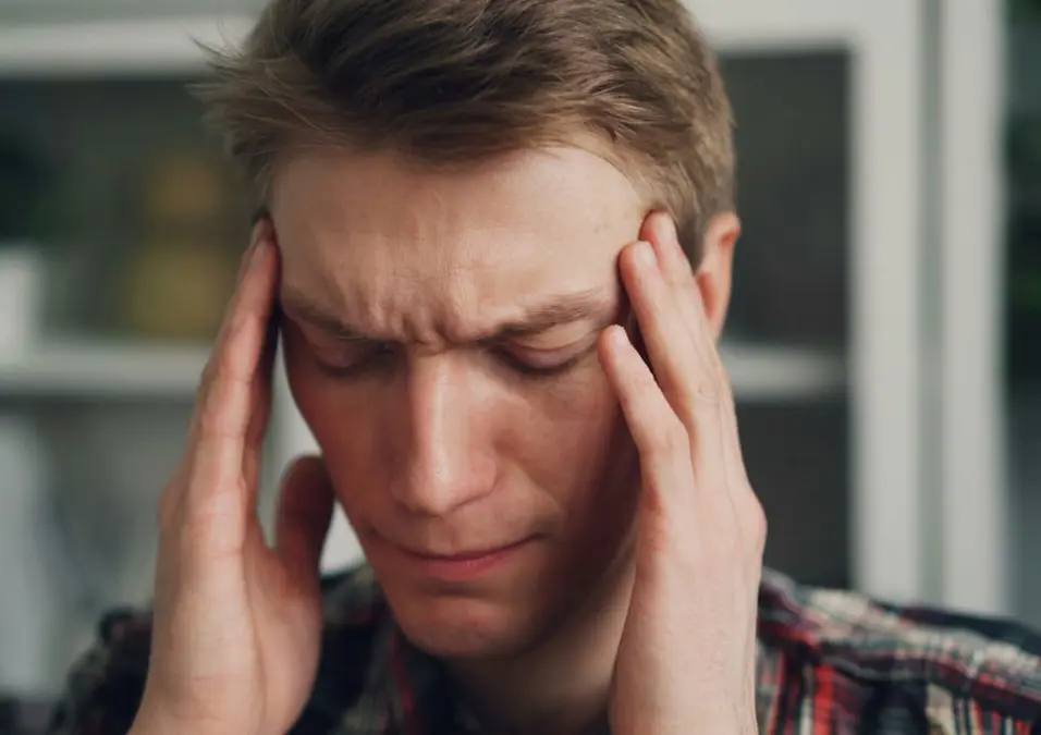رجل يمسك رأسه، يوحي بأعراض نقص الحديد عند الرجال وطرق العلاج السريعة.