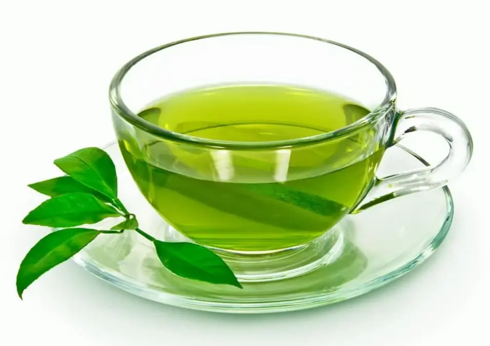 كوب زجاجي من الشاي الأخضر مع غصن صغير من الأوراق على صحن، يوحي بفوائد الشاي الأخضر للرجال.