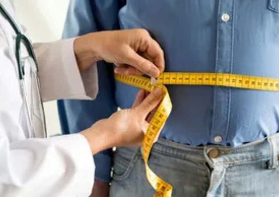 A doctor measures his patient's waist