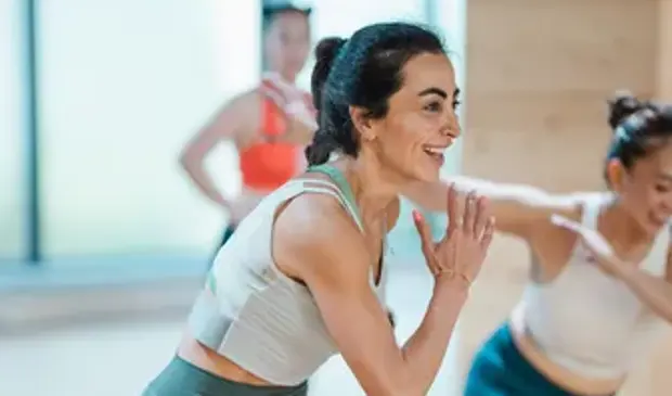 نساء يجرين تمارين الإحماء في حصة بودي كومبات في جيمنيشن استعداداً لجلسة كارديو عالية الشدة.