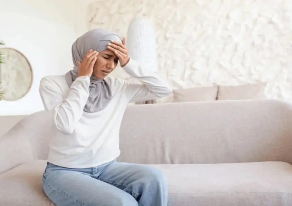شخص يمسك رأسه كما لو كان يشعر بالألم، يوحي بأعراض مرتبطة بنقص الحديد.