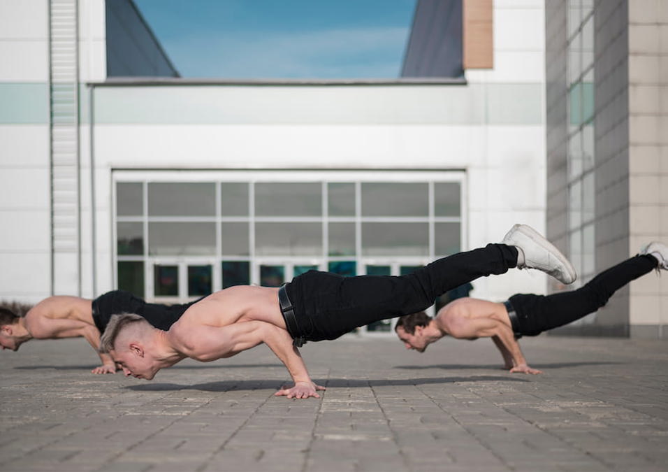 ثلاثة شباب يقومون بتمارين بوزن الجسم.