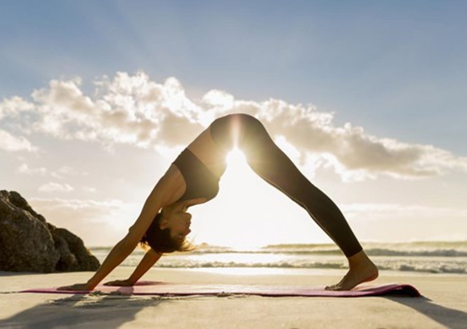 A Woman Practicing Yoga On The Beach