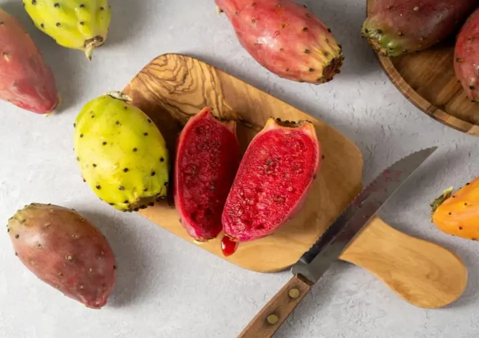  ثمار تين شوكي كاملة ومقطعة على لوح تقطيع، توحي بفوائد التين الشوكي لمرضى السكري وهل هي حقيقة أم مبالغة.