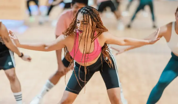 Women leading a high-energy Zumba class at GymNation, dancing in a colorful studio with other participants in the background
