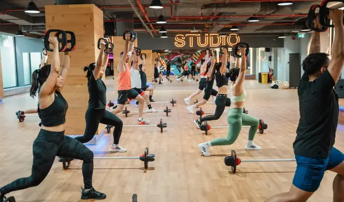 مجموعة من الأشخاص يؤدون تمارين ليس ميلز بودي بامب في جيمنيشن دبي، باستخدام القضبان