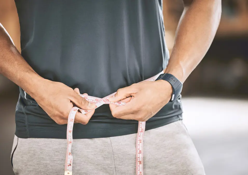 Man measuring waist with tape measure