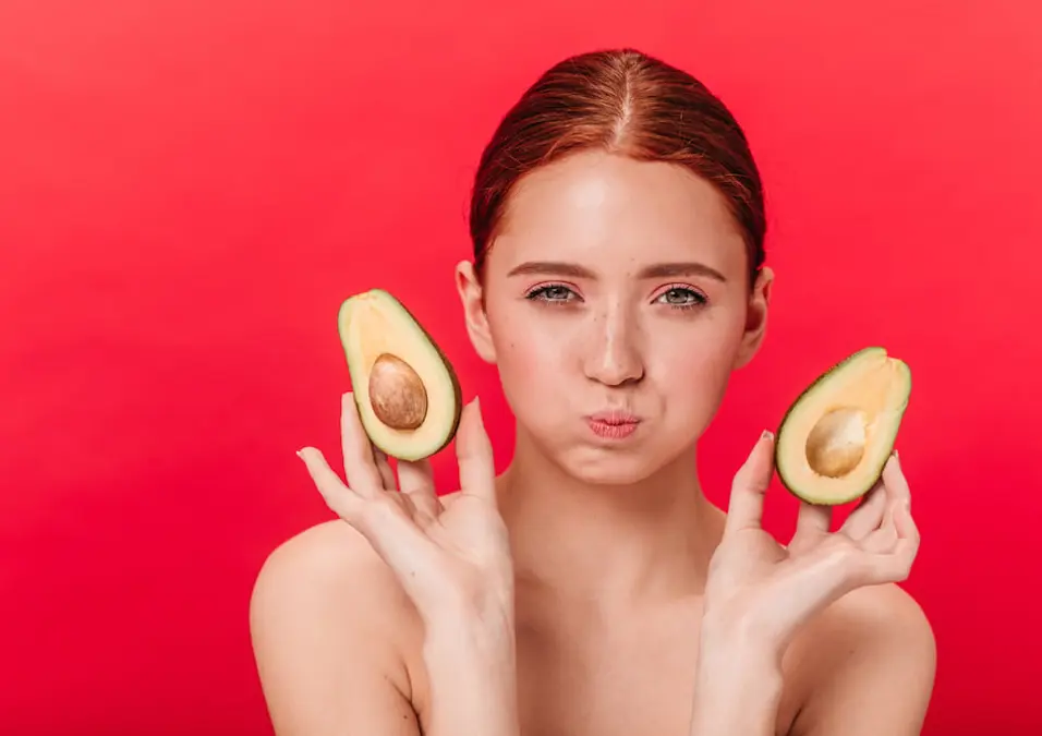 امرأة تحمل نصفي أفوكادو بتعبير وجه متجهم، توحي بأضرار الأفوكادو المحتملة ومتى يجب الحذر.