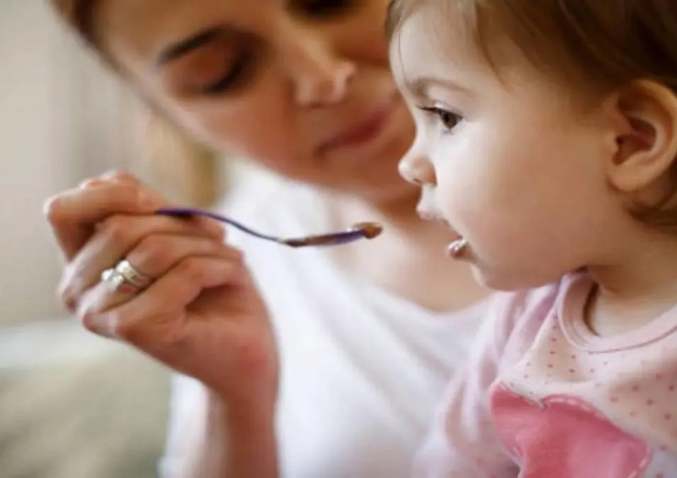 أم تطعم طفلها ملعقة من طعام داكن اللون، مما يوحي بفوائد الشمندر للأطفال، متى يُقدَّم وكيف يُستخدم بأمان.