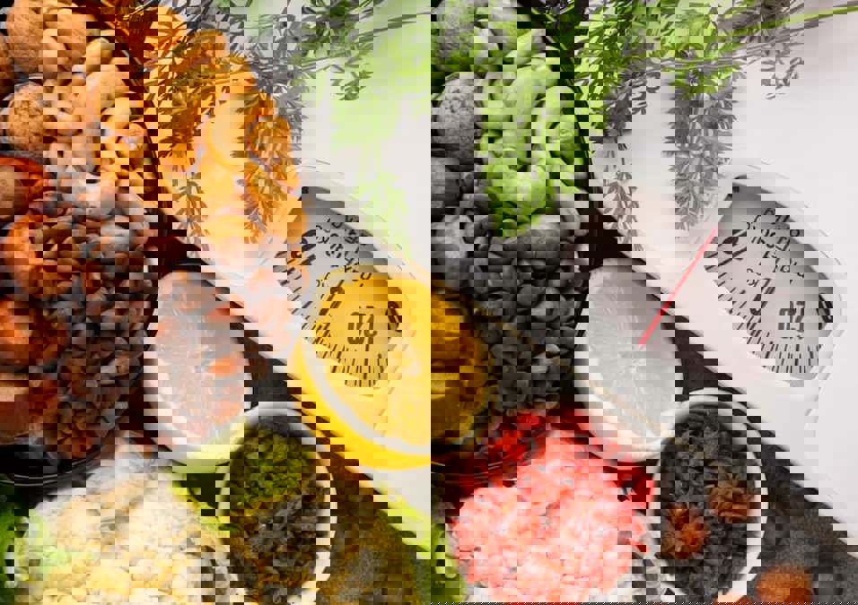 ميزان محاط بأطعمة غنية بالدهون الصحية يظهر فقدان الوزن.