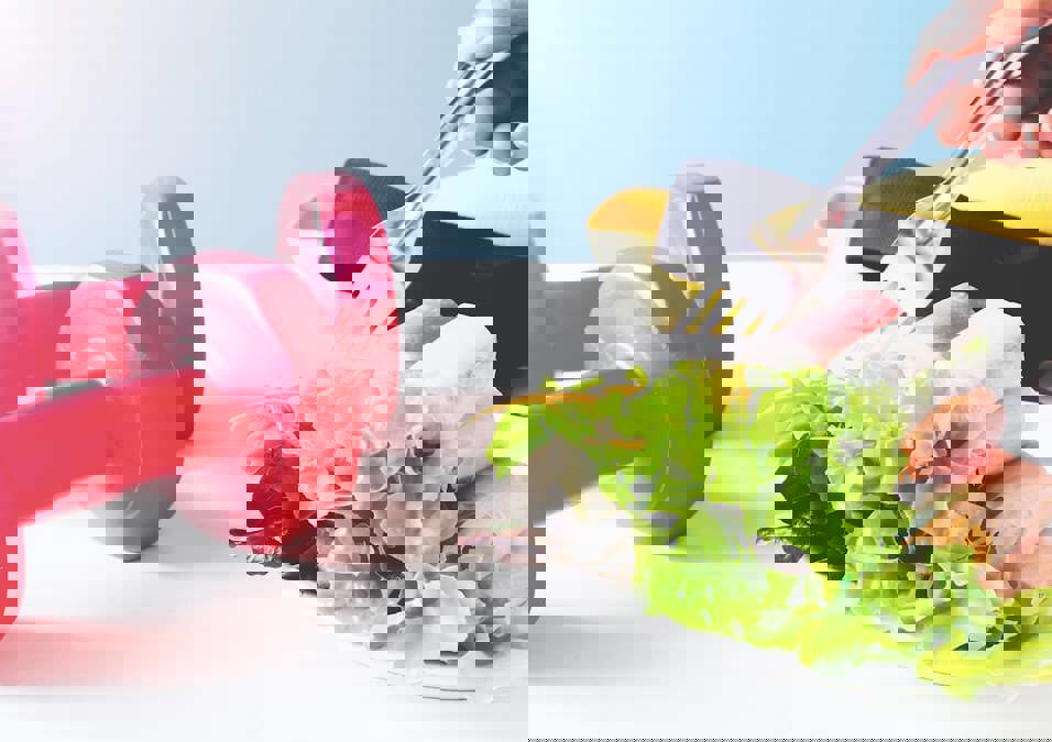 طبق من السلطة الطازجة ولفائف الربيع بجانب أوزان، يشير إلى برنامج غذائي للمبتدئين لبناء العضلات.